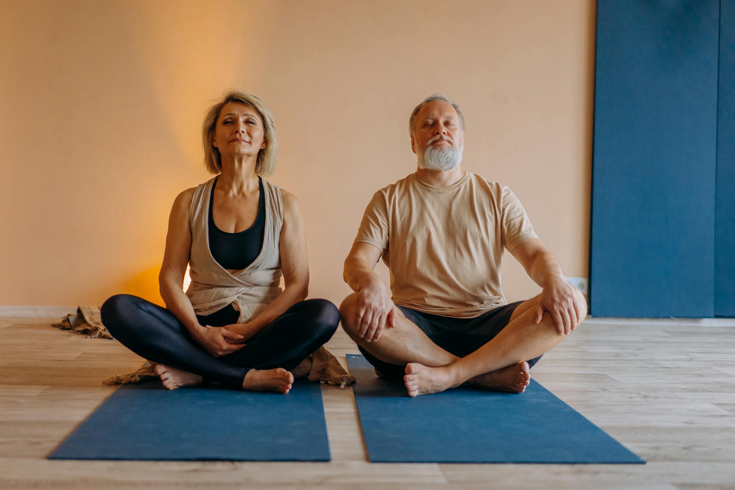 An elderly couple meditating in a yoga studio, promoting wellness and relaxation.